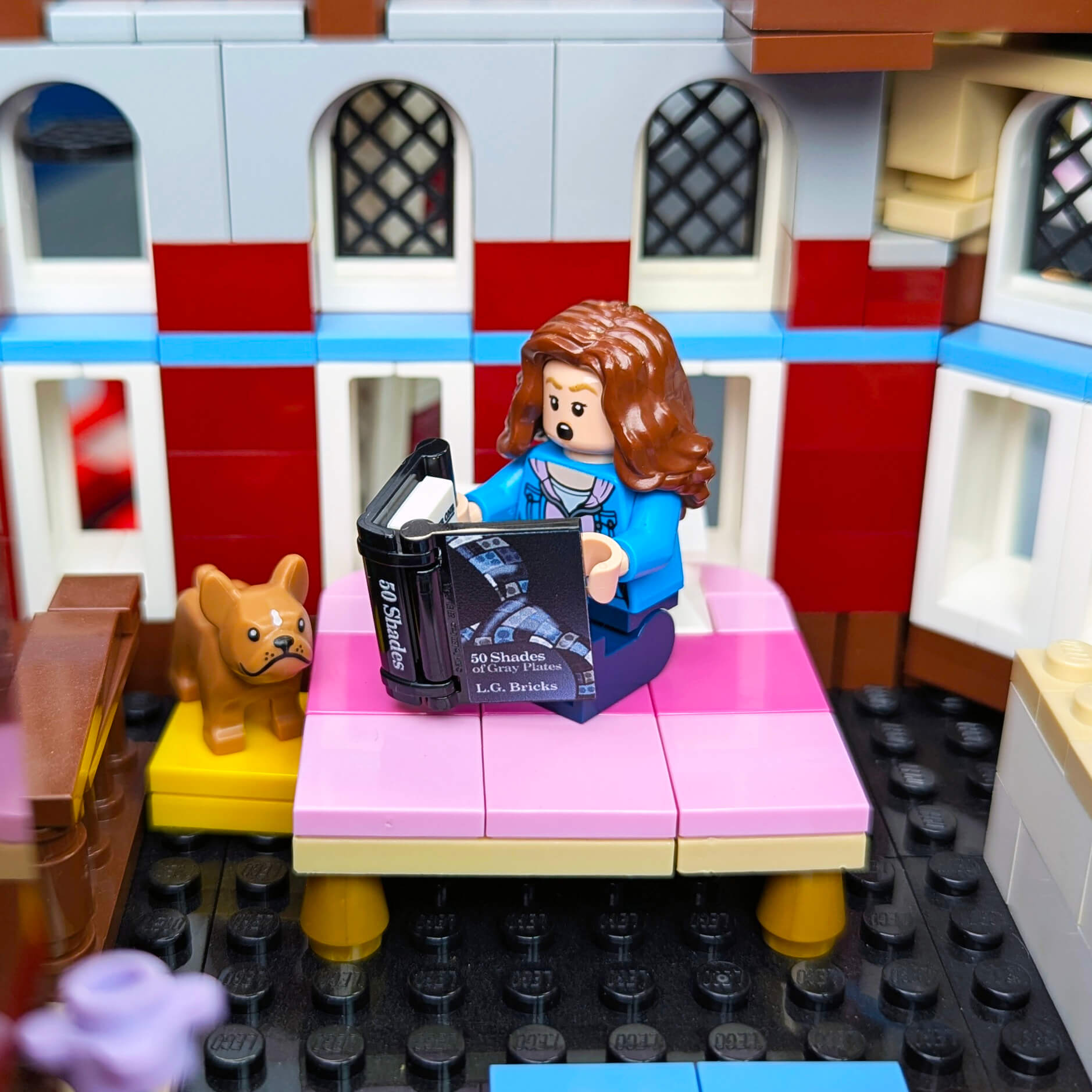 LEGO figure in bed with a book and dog 