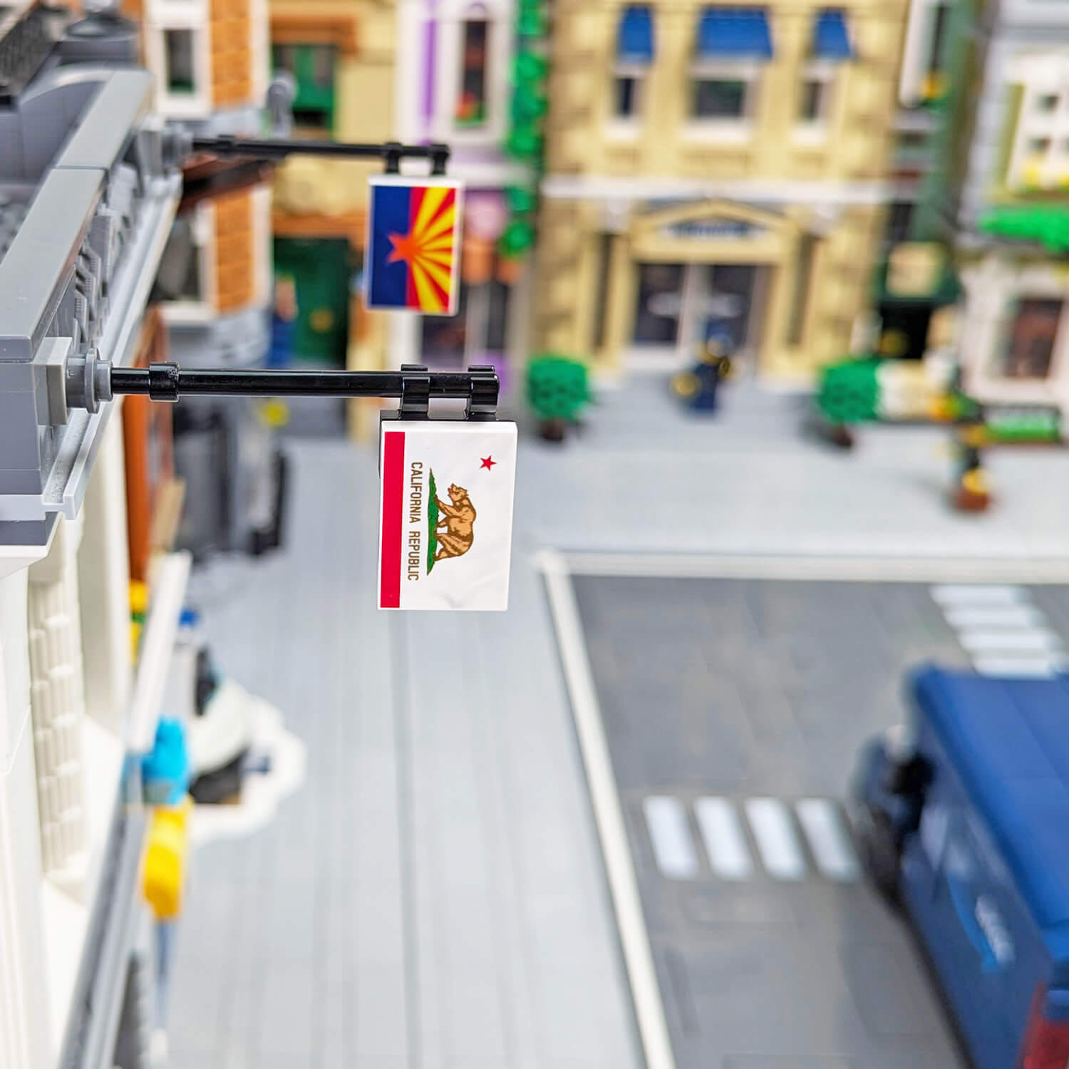 Lego city street with a California flag, featuring a blurred background of buildings and vehicles.