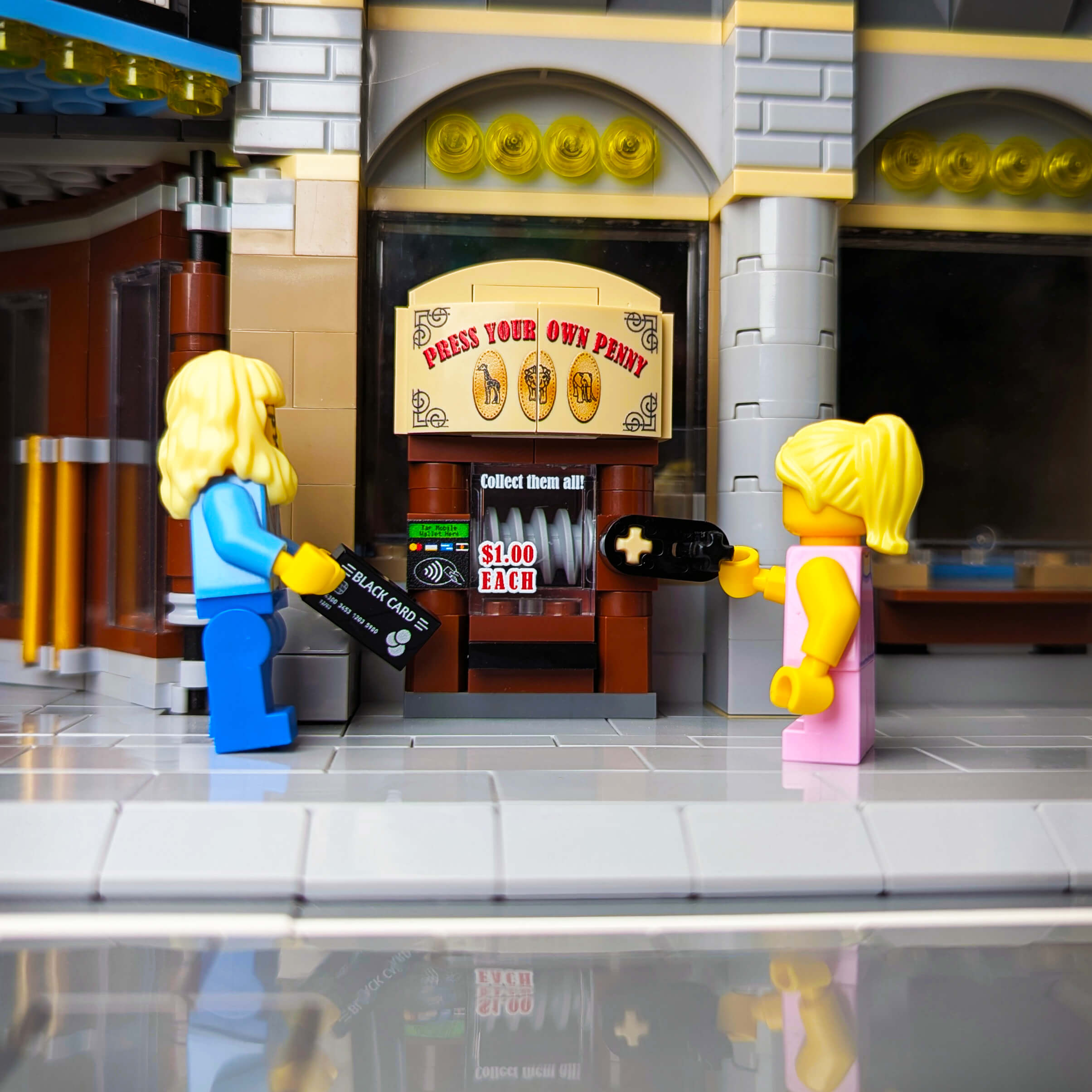 Two LEGO figures interacting with a custom printed penny press LEGO® set