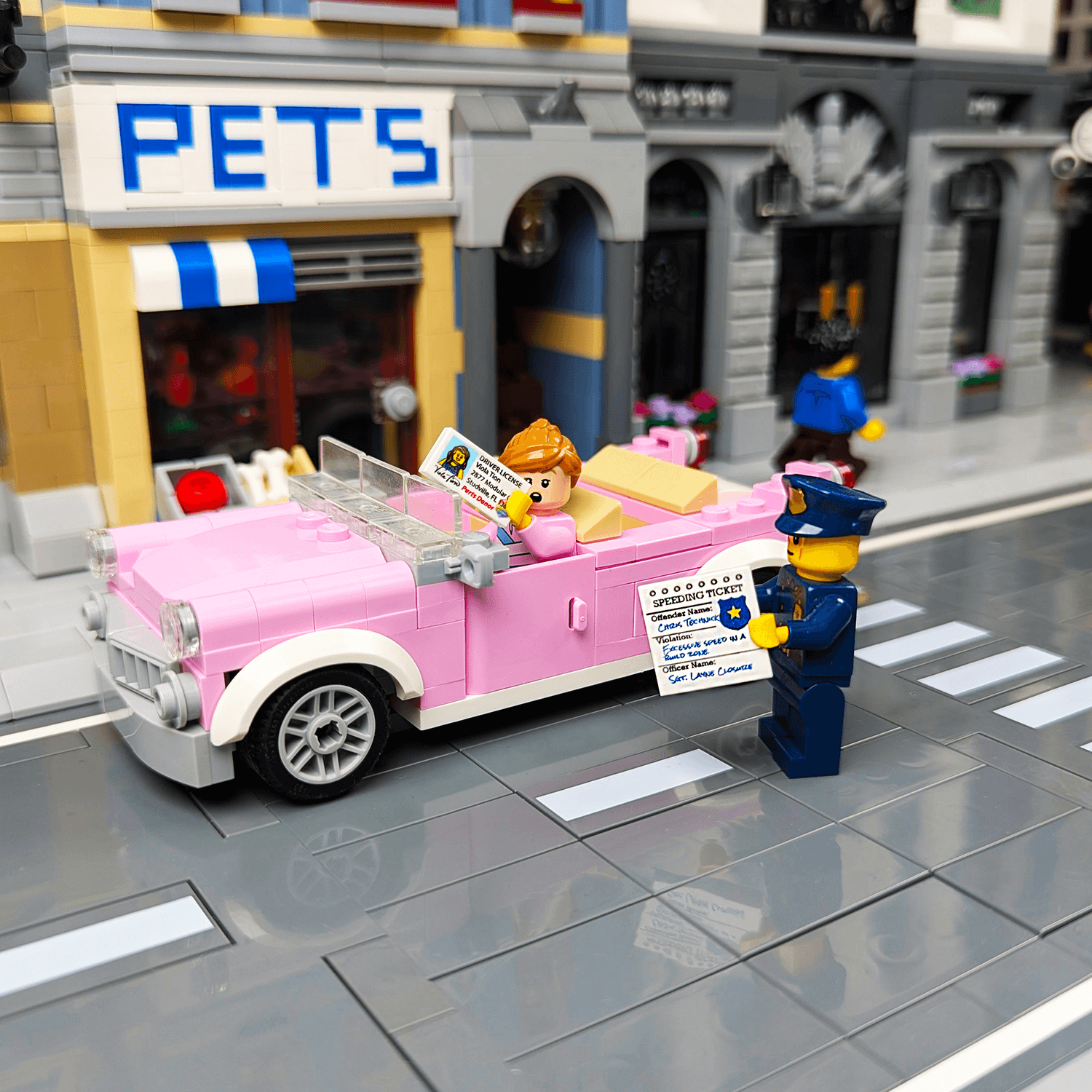 LEGO scene with a pink car, police officer holding a speeding ticket