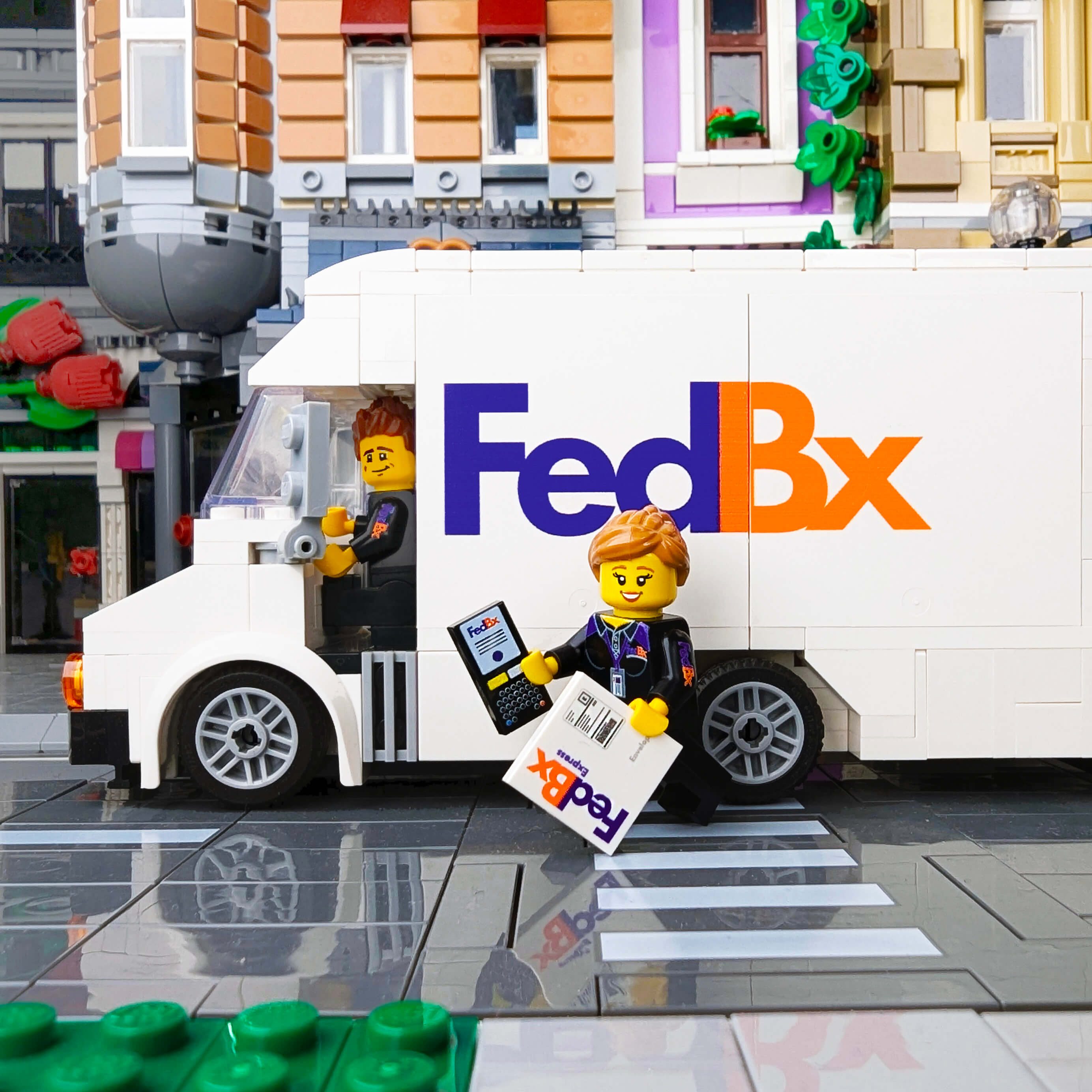 Custom Male and Female Delivery drivers wearing FedBx black clothing, in front of a brick built FedBx truck.
