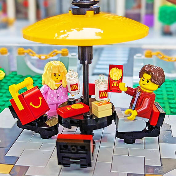 LEGO figures at a McDonald's restaurant with a yellow umbrella and food items.