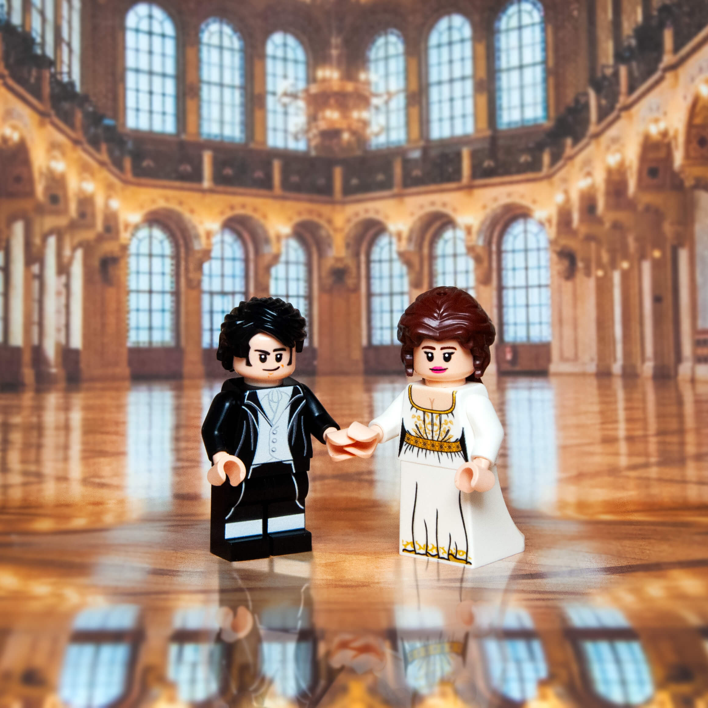 Two LEGO figures in a grand hall with high ceilings and large windows.