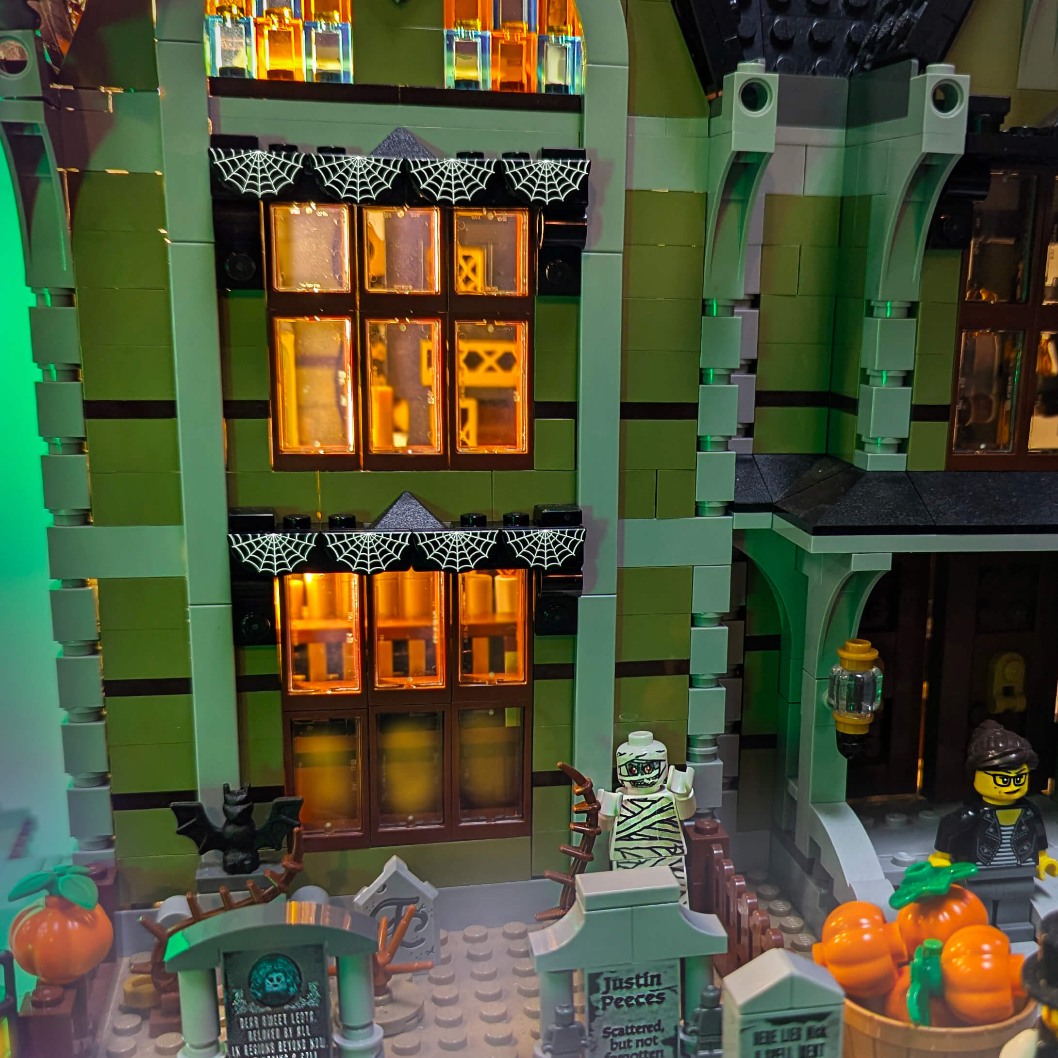 Toy haunted house with Halloween decorations and characters, featuring green and orange colors.