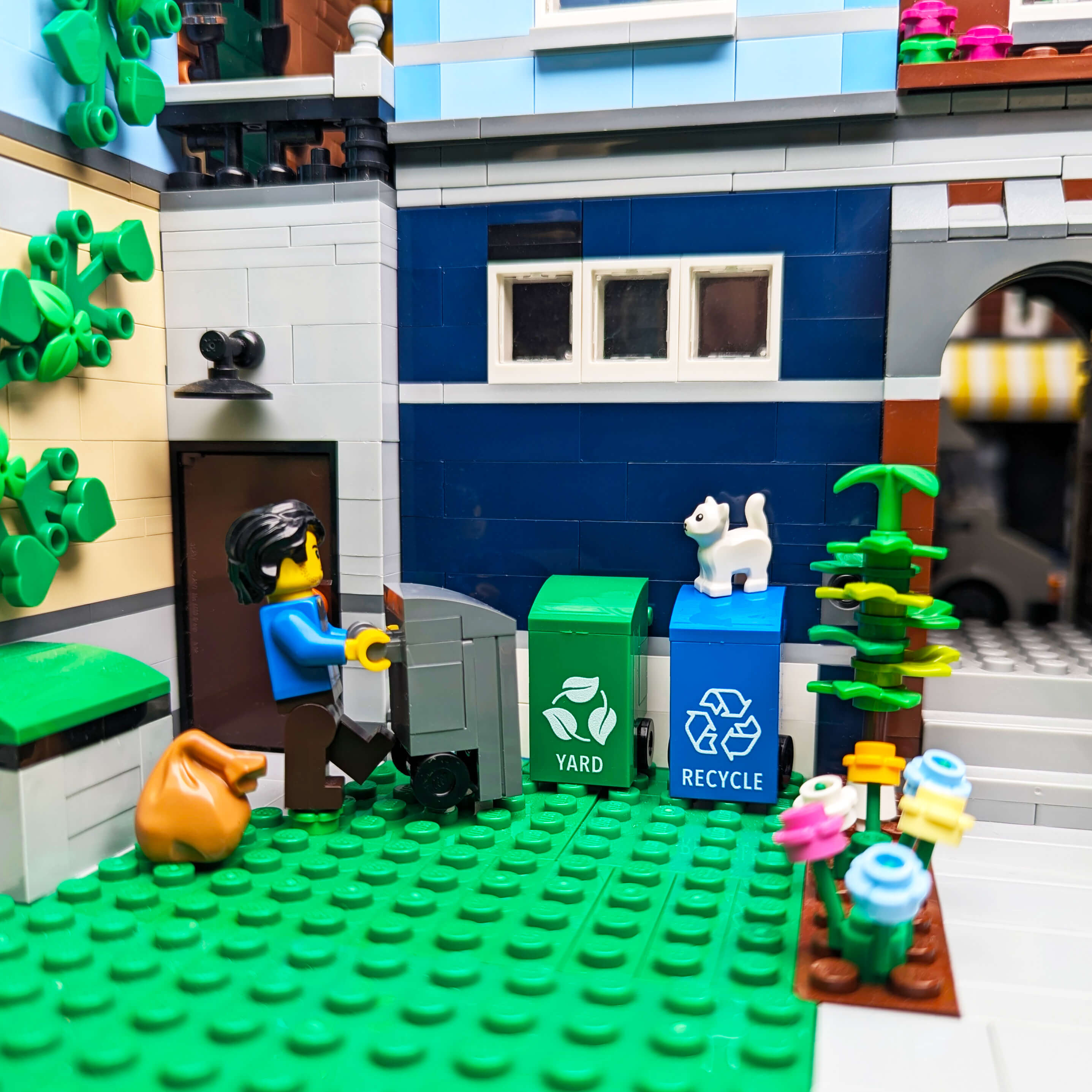 LEGO scene with a minifig interacting with recycling bins in an urban setting