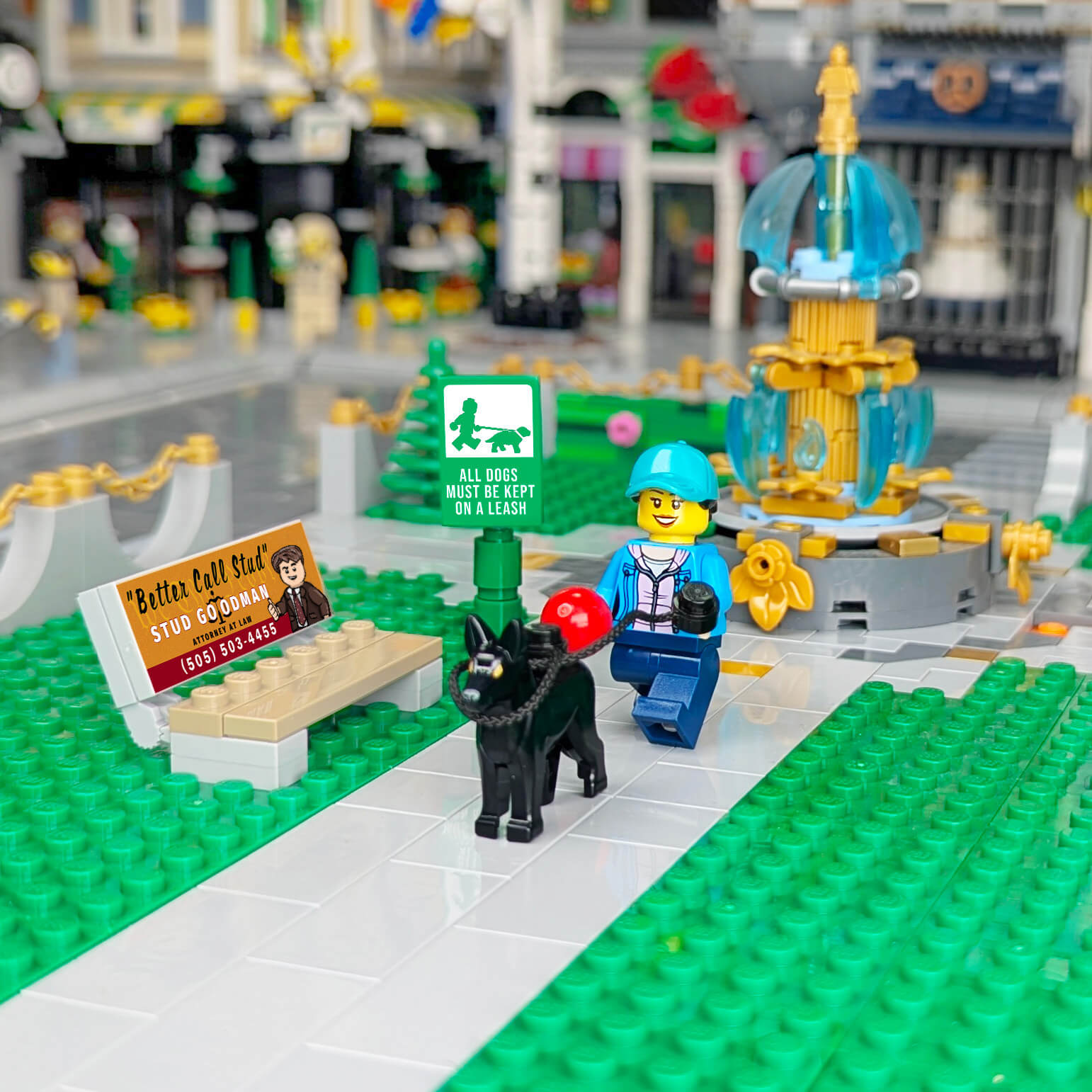 LEGO scene with a dog, person, bench and sign in an urban setting