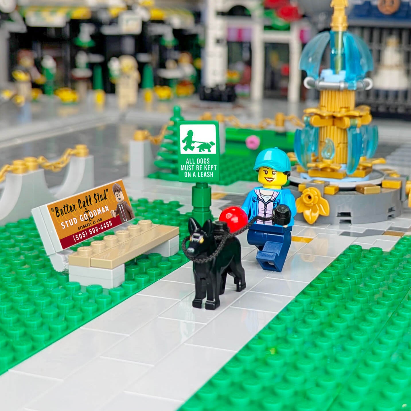 LEGO scene with a dog, person, bench and sign in an urban setting