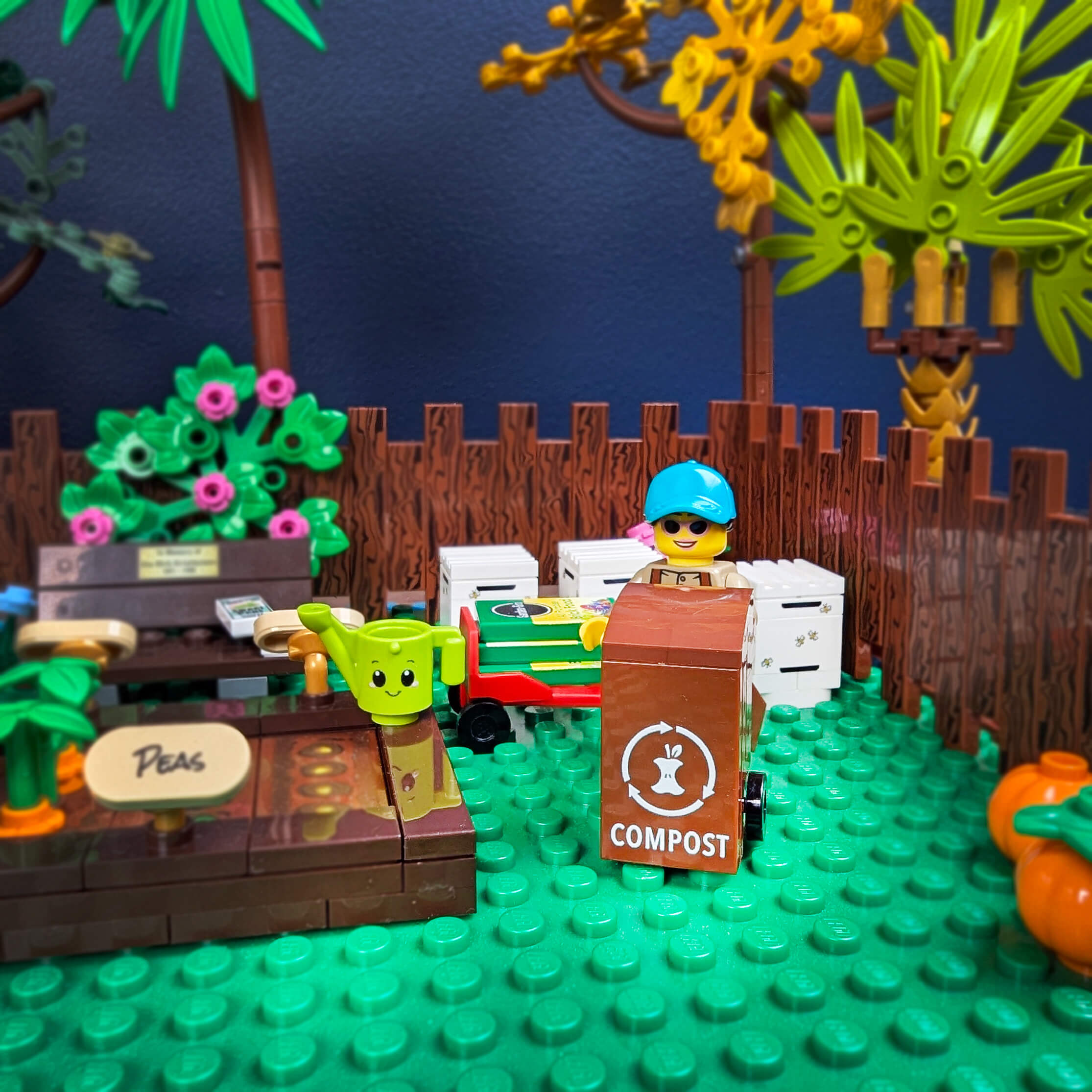 LEGO garden scene with a character in a blue hat, a green plant, and compost bin on a green base.
