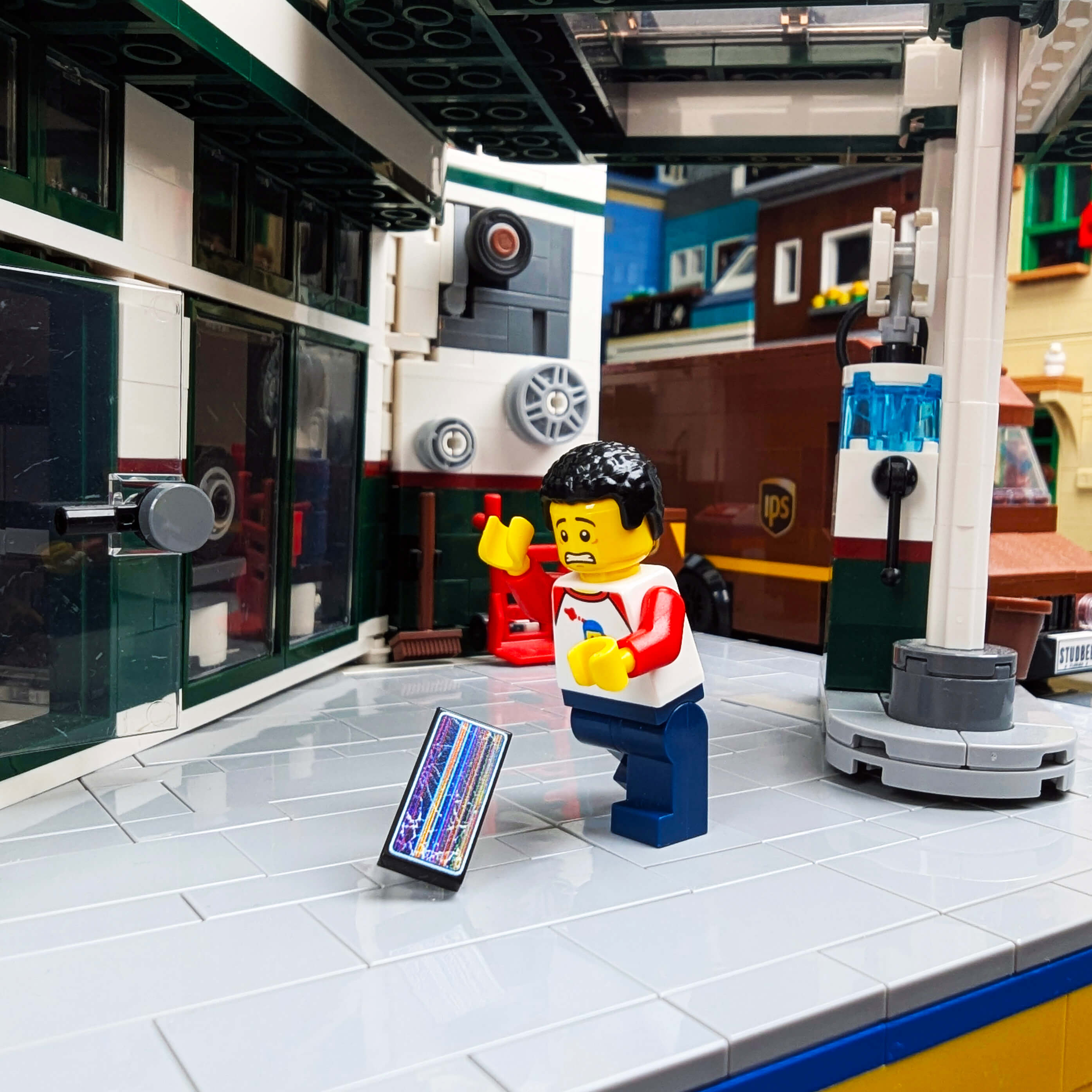 LEGO figure trying to catch a dropped phone with a cracked screen