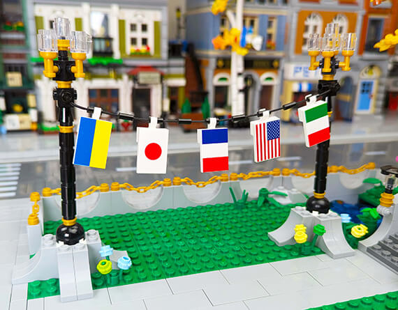 LEGO model of a street with flags hanging from various countries, set against a blurred lego cityscape background.
