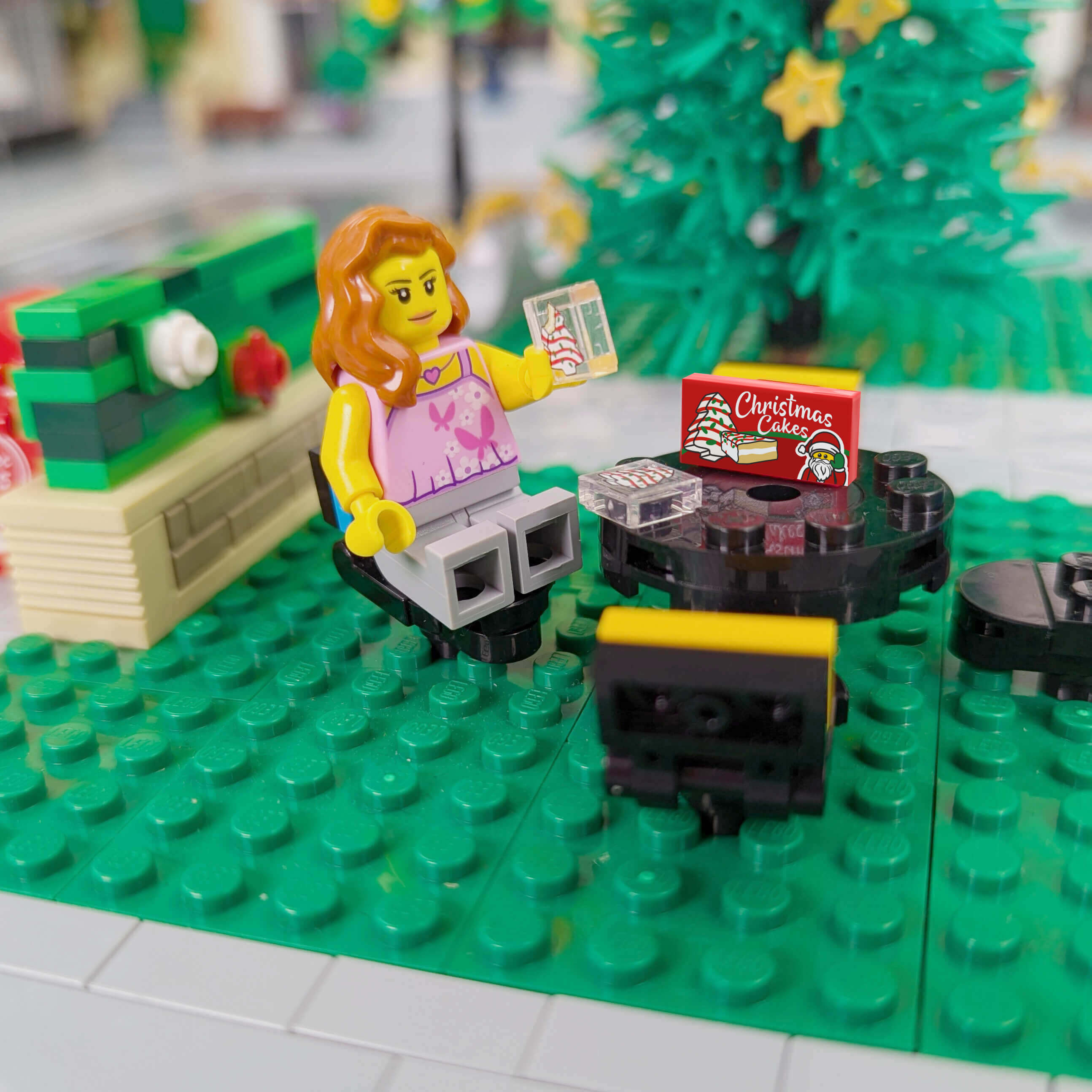 minifig sitting at a picnic table with a Christmas cake box and is eating Christmas cakes.