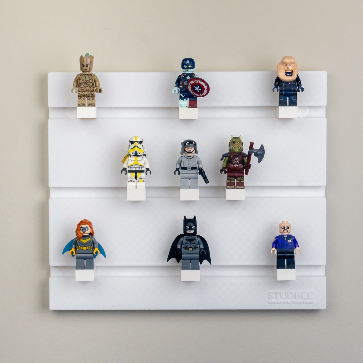 A wall-mounted display shelf with three tiers holds nine character mini-figures, including a humanoid tree and a superhero with a shield.
