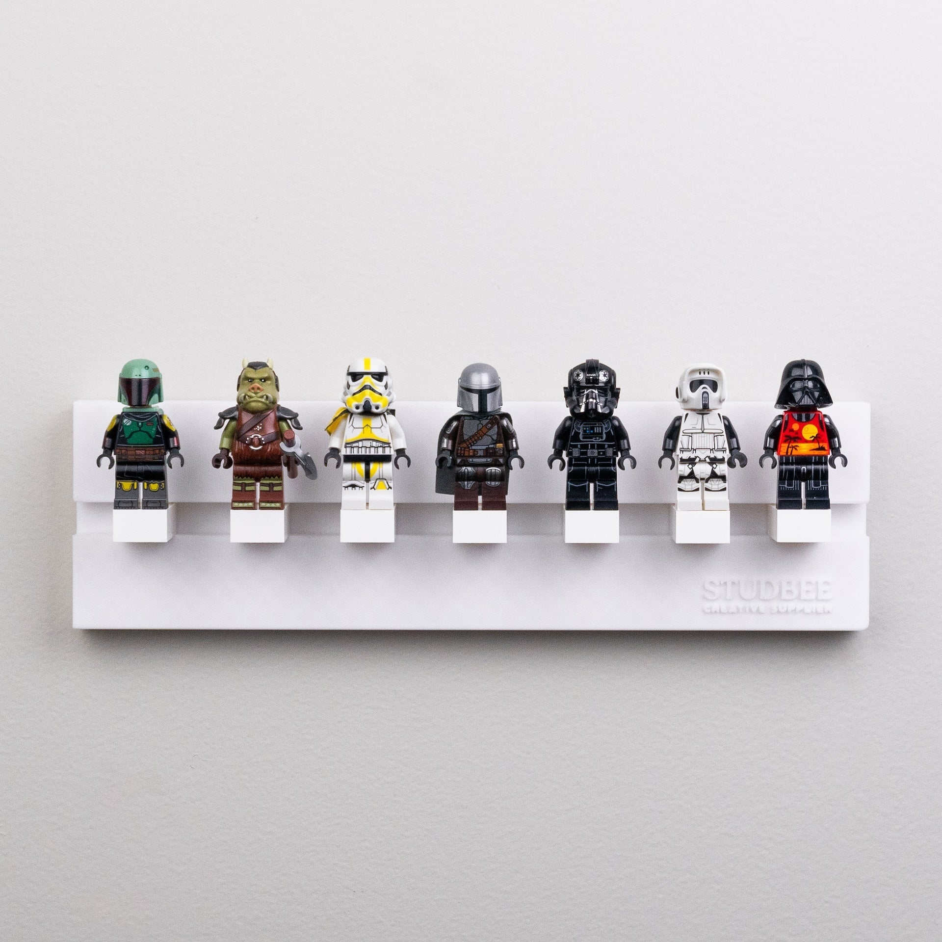A row of seven themed mini-figures on a white single-tier shelf, including characters in armor and helmets.