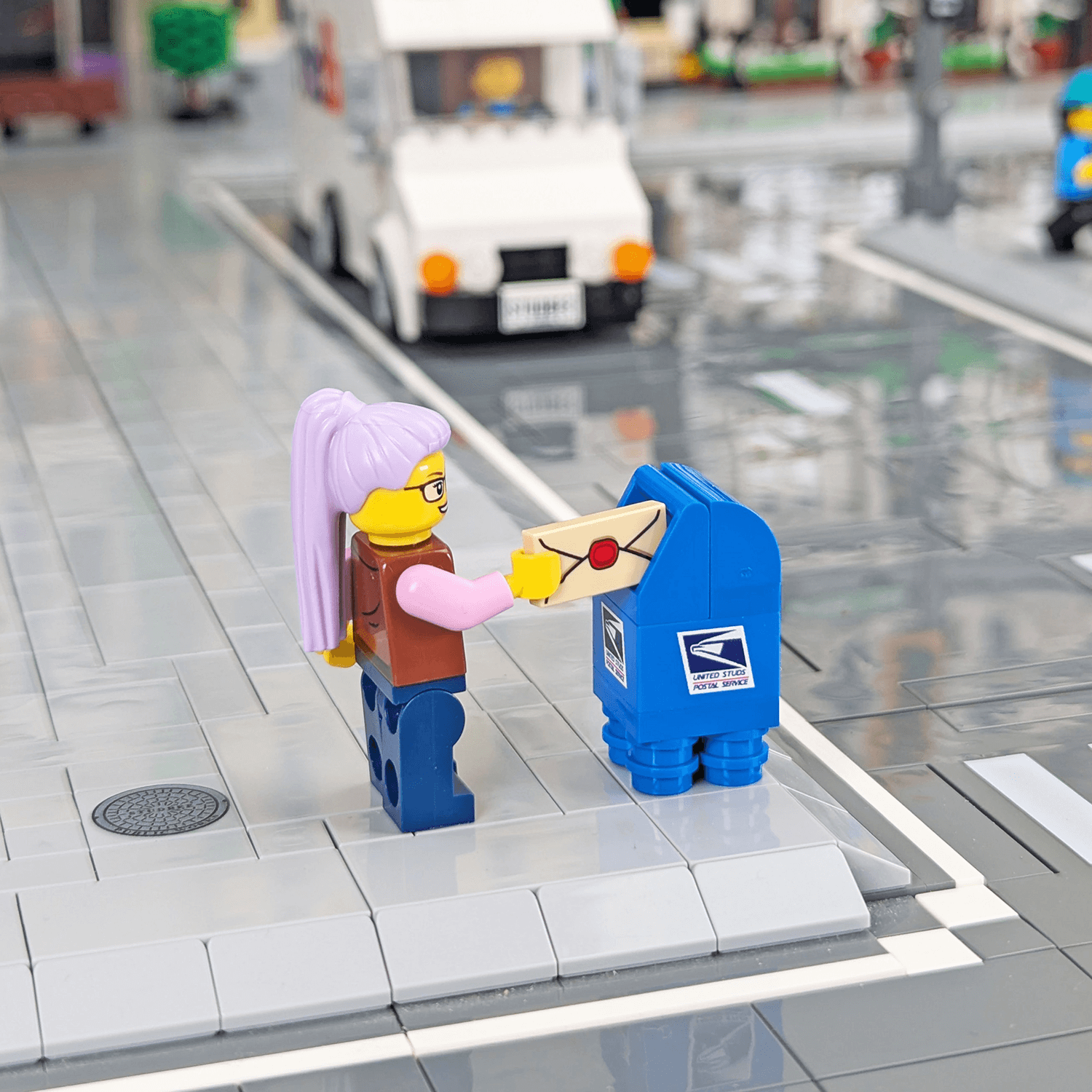 LEGO figure of a person with purple hair and a LEGO mailbox on a transparent platform.