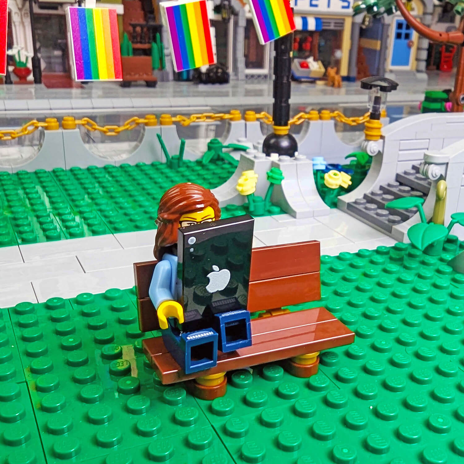 minifig with a black tableton a green baseplate with a cityscape background