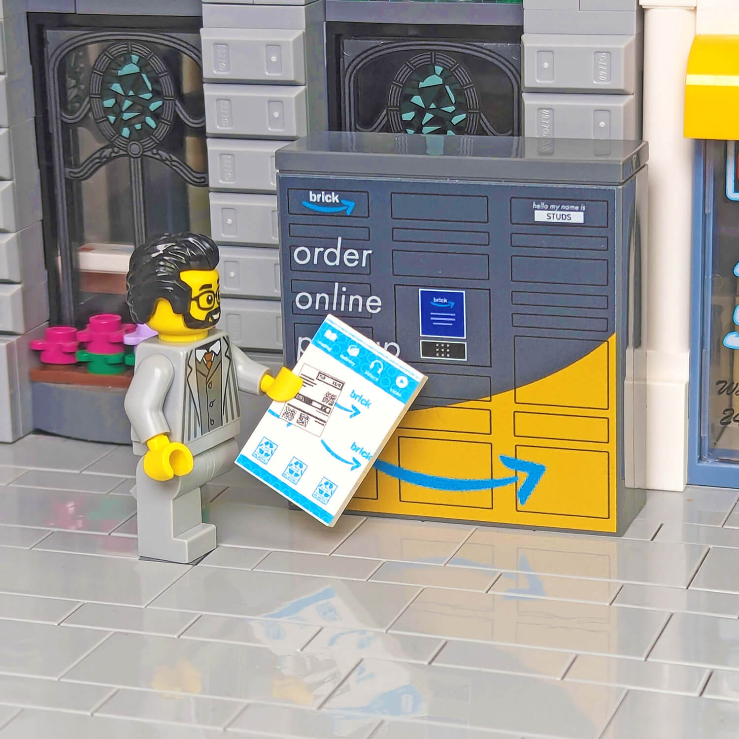 minifig holding a amazing poly mailer in front of a brick-and-mortar store with an Amazon locker.