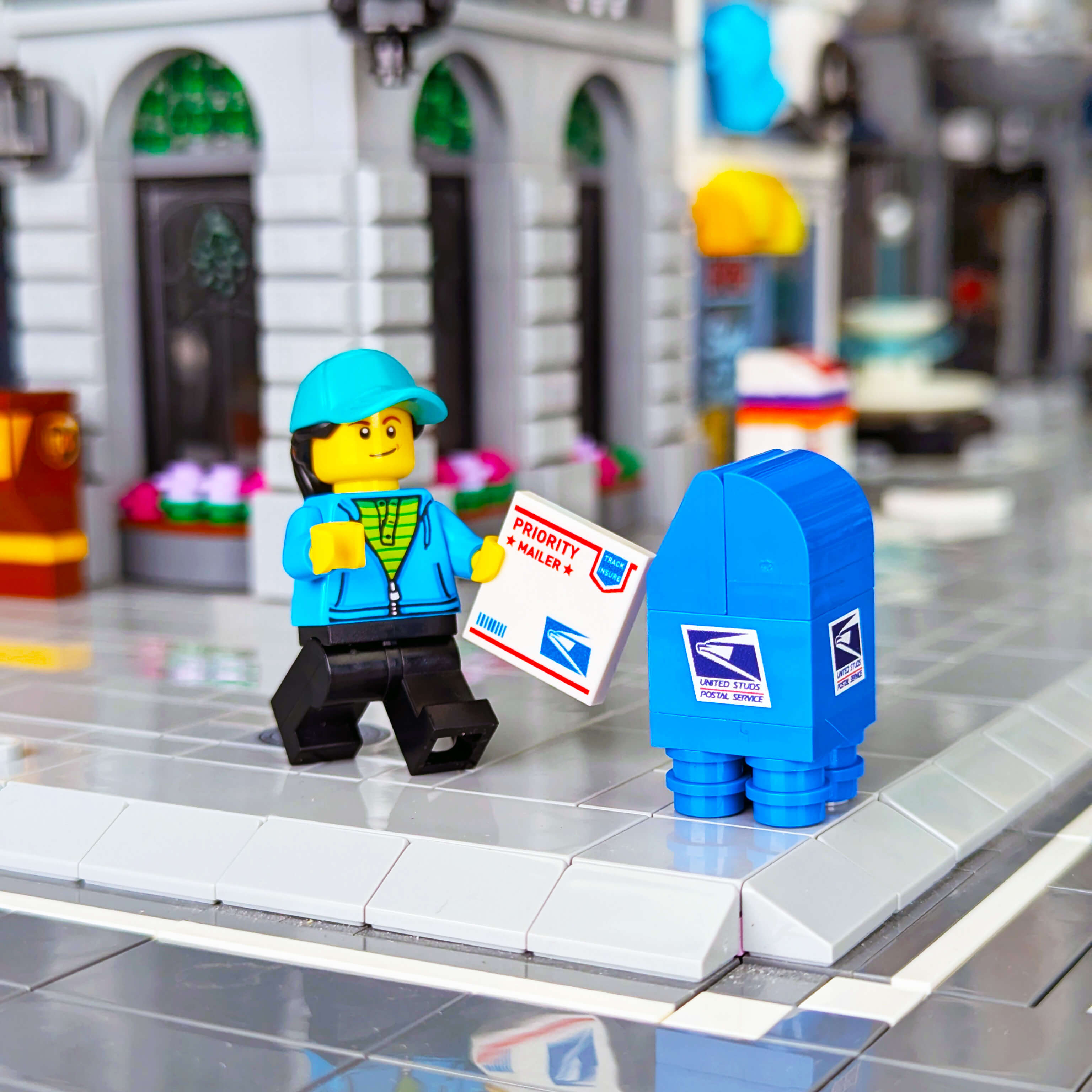 Minifig with a blue mailbox and Priority Mail box in a toy city setting