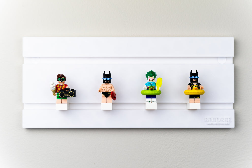 a lego wall display of 5 minifigures:  a robin, batman with a speedo, the joker with a floatie, and a batman with a floatie