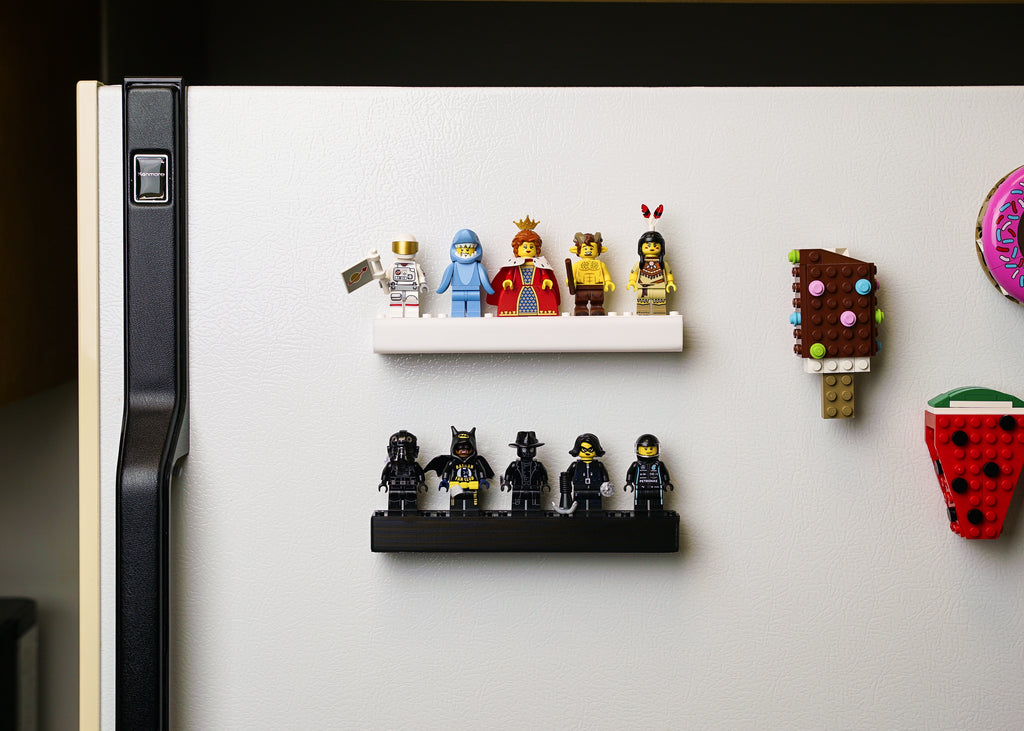 two small magnetic shelfs displaying assorted lego minifigures on a home refrigerator