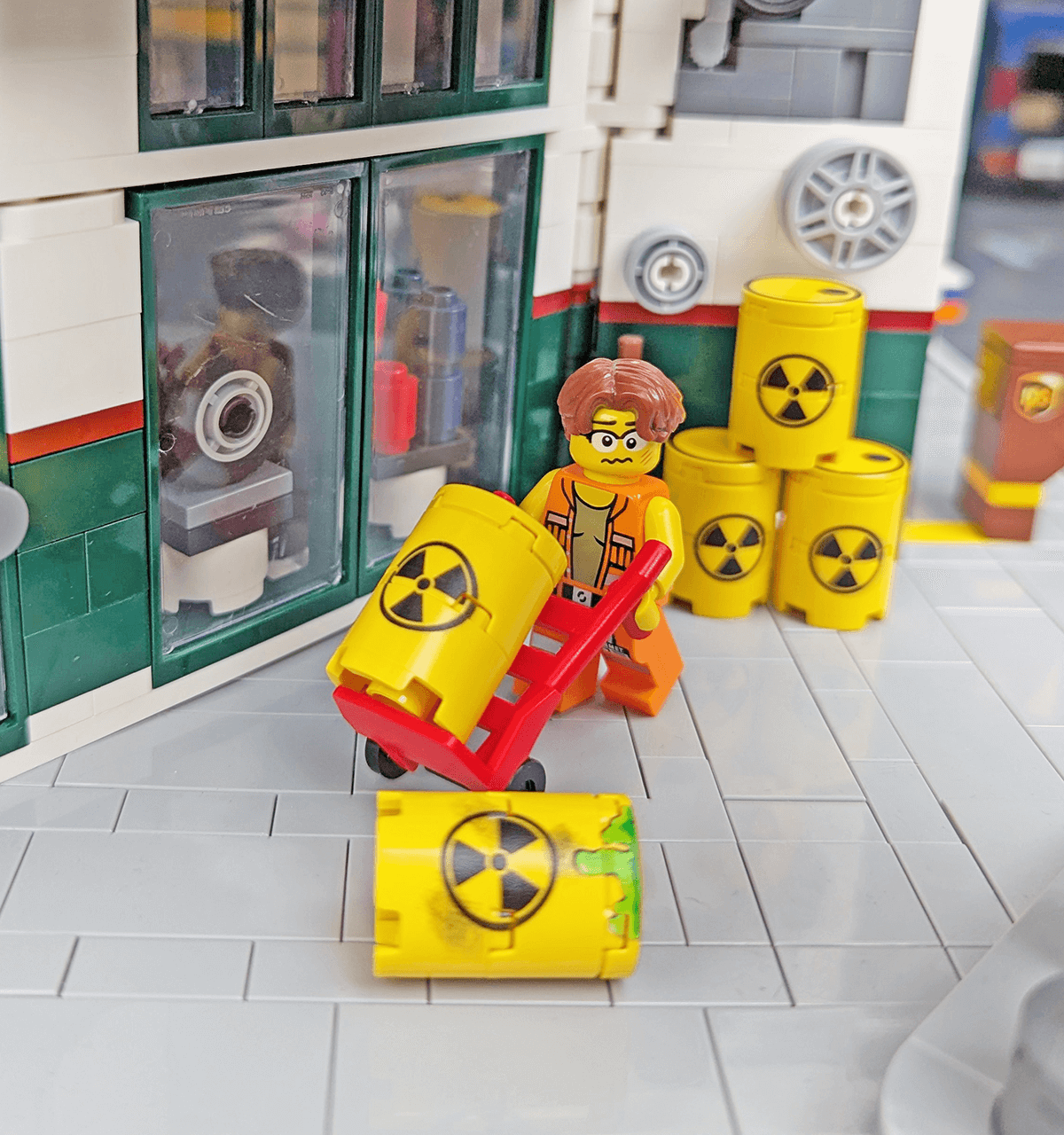 LEGO figure moving radioactive barrels around with a radiation warning sign container in a toy setting