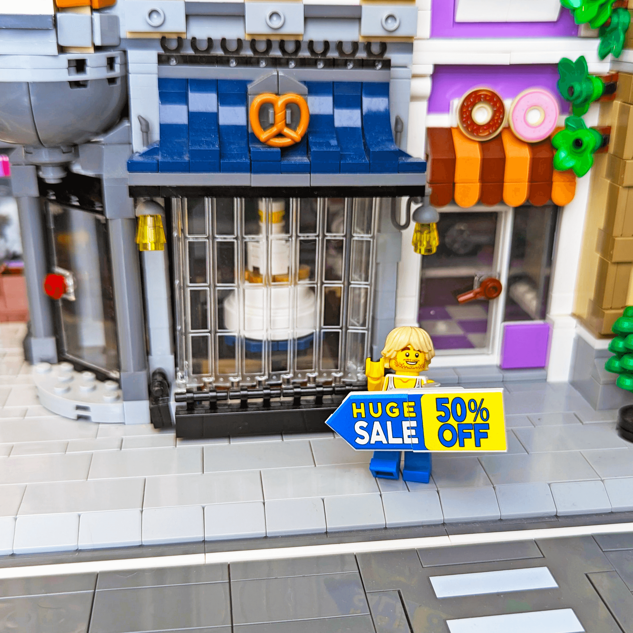 Store with LEGO figures and a 'Huge Sale 50% Off' sign