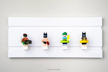 studbee minifigure wall display showcasing the following Lego figures: robin in beach attire, batman in speedos, the joker in a floatie holding a popsicle, and another batman in a yellow duck floatie.