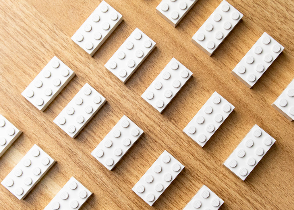A few white lego bricks, 2 by 4 size displayed on a table diagonally. 